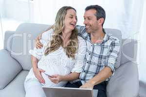 Expecting couple sitting on sofa