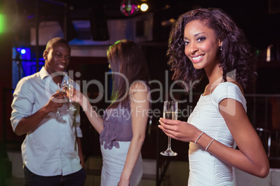 Young woman having champagne in bar and her friends toasting gla