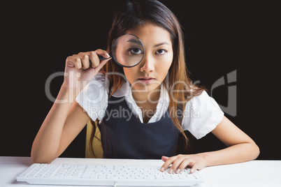 Serious businesswoman looking through magnifying glass