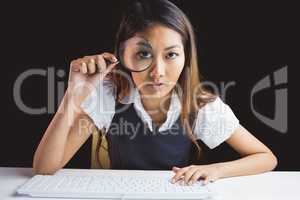 Serious businesswoman looking through magnifying glass