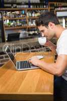 Handsome man using laptop and having coffee