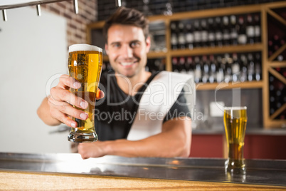 Handsome barman holding a pint of beer