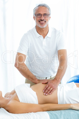 Pregnant woman receiving a stomach massage from masseur