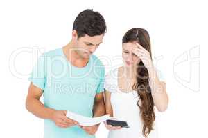 Young couple using calculator for paying bills