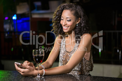 Beautiful woman typing a text message while having wine