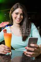 Beautiful woman typing a text message while having cocktail