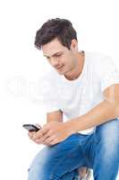 Handsome man crouching using a smartphone