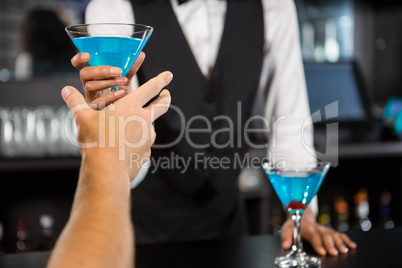 Bartender serving blue cocktail at bar counter