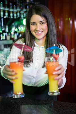 Portrait of pretty bartender serving cocktail at bar counter