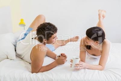 Young couple having breakfast on bed