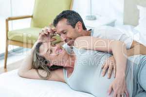 Expecting couple lying on bed and chatting