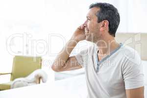 Man talking on smartphone in bedroom