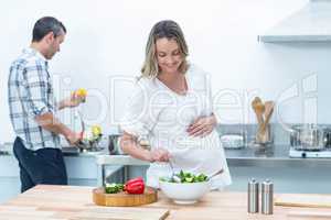 Pregnant woman making a salad in the kitchen
