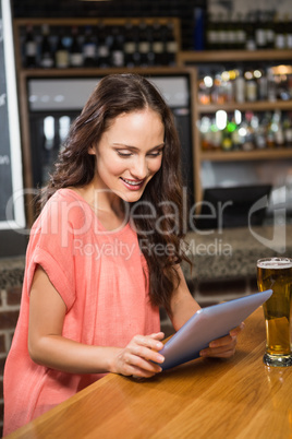 Pretty woman having a beer and looking at tablet