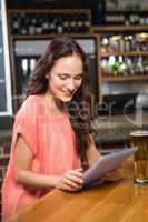 Pretty woman having a beer and looking at tablet