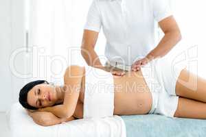 Pregnant woman receiving a back massage from masseur