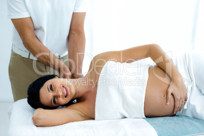 Pregnant woman receiving a back massage from masseur