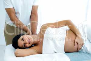 Pregnant woman receiving a back massage from masseur