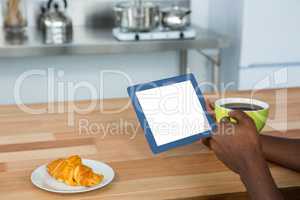 Man using digital tablet while having breakfast
