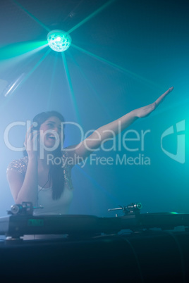 Pretty female DJ waving her hand while playing music