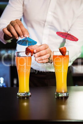 Bartender garnishing cocktail with strawberry