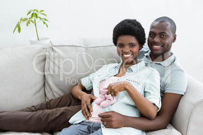 Pregnant couple holding pink baby shoes