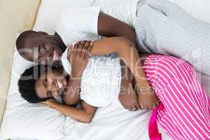 Pregnant couple cuddling on bed