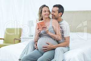 Expecting couple sitting on bed