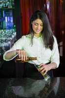 Pretty bartender preparing a drink at bar counter