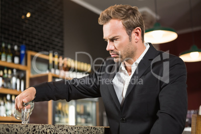 Tired man pouring a shot of alcohol