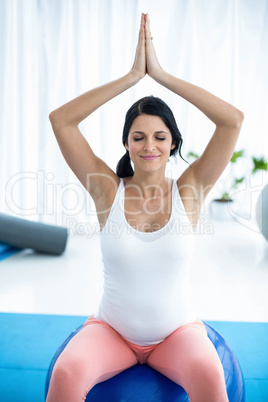 Pregnant woman in prayer position on exercise ball
