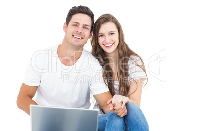 Young couple sitting on floor using laptop