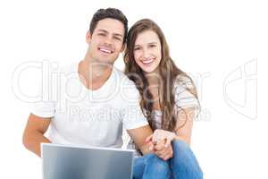 Young couple sitting on floor using laptop