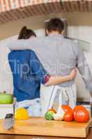 Vegetables on chopping board and couple embracing