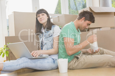 Young couple eating noodle and using laptop