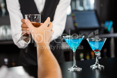 Bartender serving whiskey at bar counter