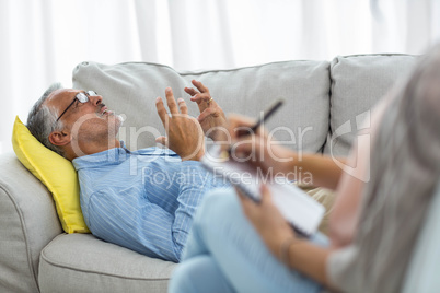 Female doctor writing on notepad while consulting a man