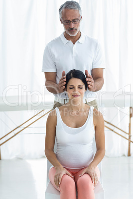 Pregnant woman receiving a head massage from masseur