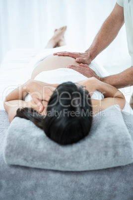 Pregnant woman receiving a stomach massage from masseur