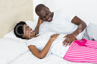 Man touching pregnant womans stomach while relaxing on bed