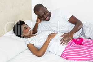 Man touching pregnant womans stomach while relaxing on bed