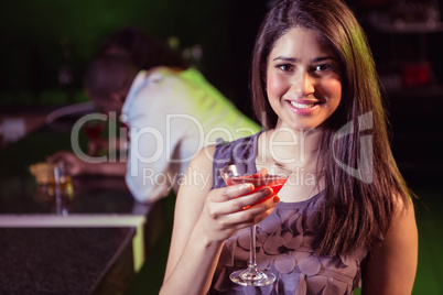 Young woman having cocktail at bar counter