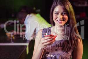 Young woman having cocktail at bar counter