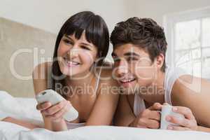 Young couple watching television together on bed