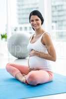 Pregnant woman touching her stomach while exercising