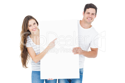 Happy couple pointing a white poster