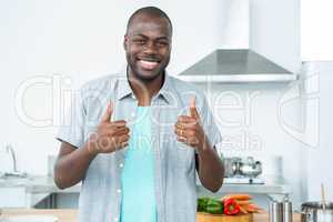 Smiling man gesturing thumbs up in kitchen