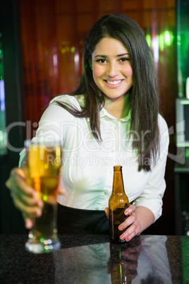 Portrait of pretty bartender serving beer at bar counter