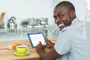 Man using digital tablet while having breakfast