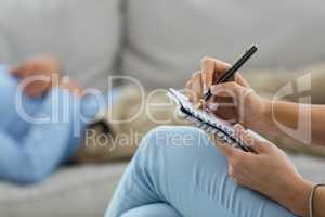 Female doctor writing on notepad while consulting a man